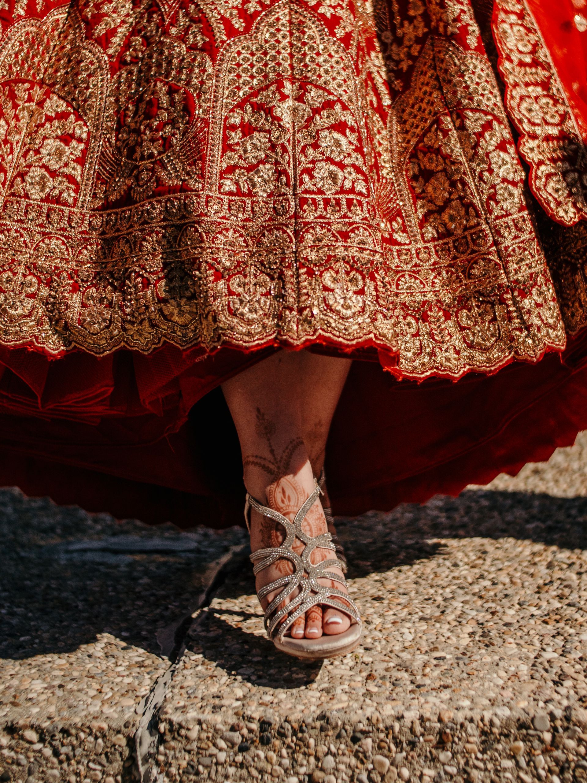 A woman is wearing a red and gold dress and sandals.