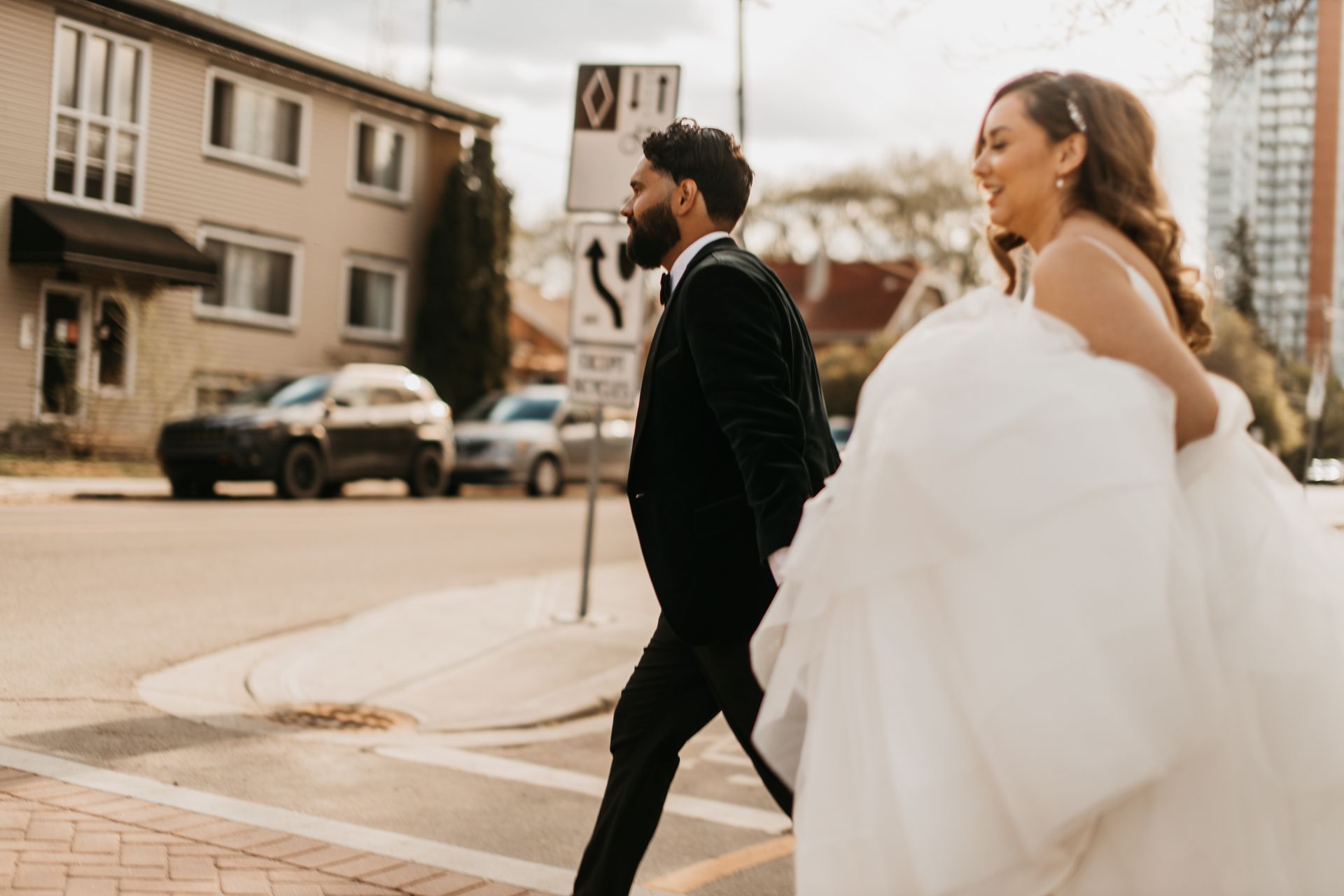 A bride and groom are walking across a street.