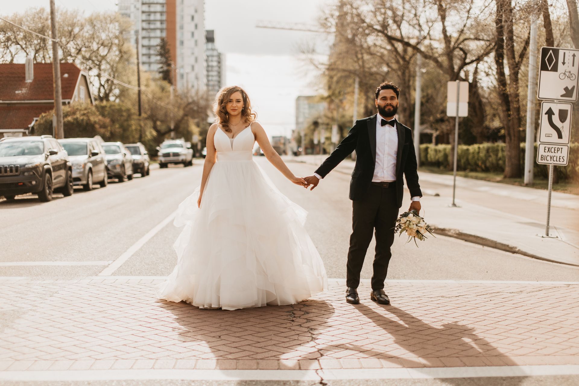 A bride and groom are holding hands while crossing a street.