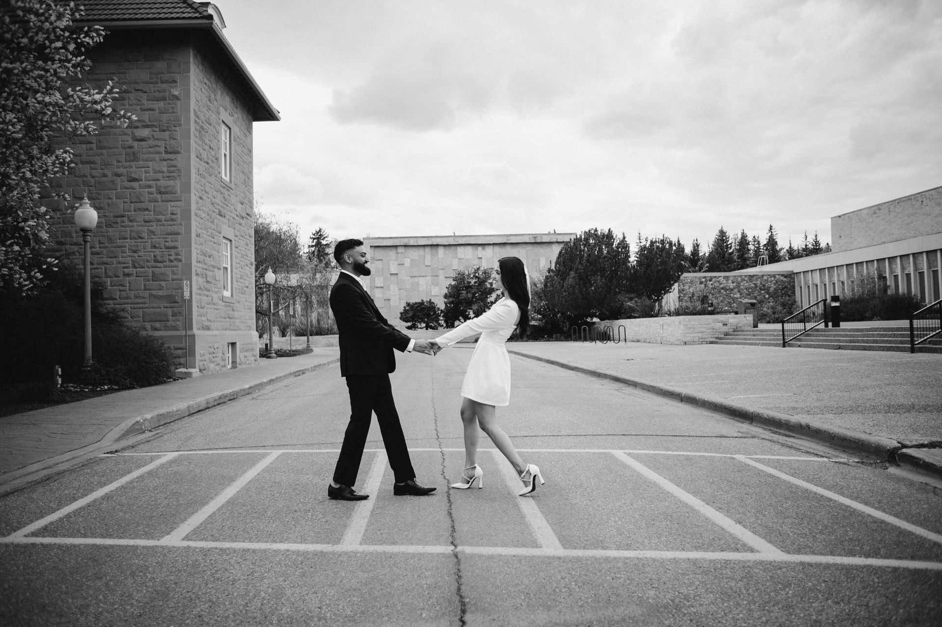 A black and white photo of a man and woman dancing in a parking lot.