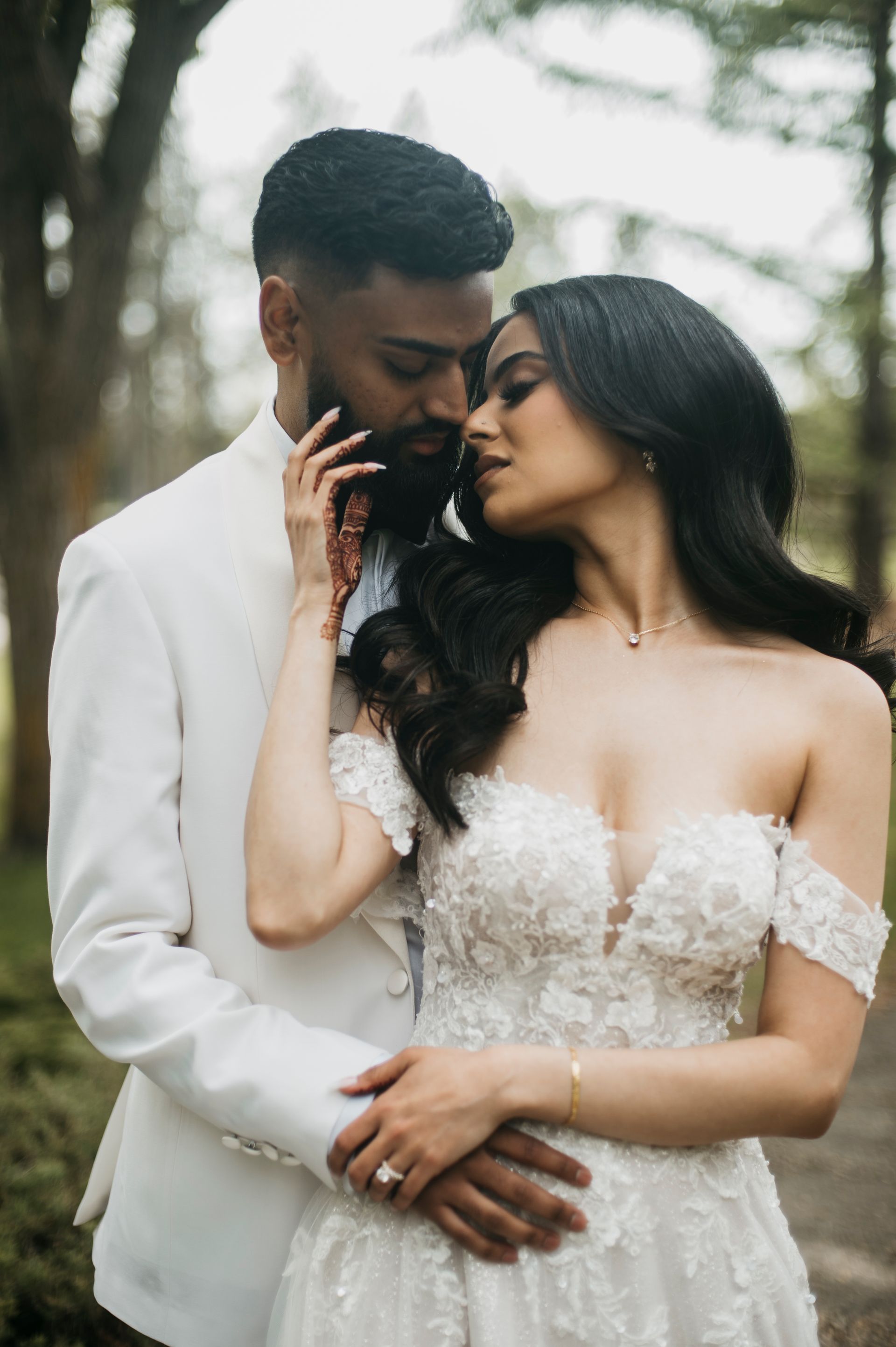 A bride and groom are posing for a picture in the woods.