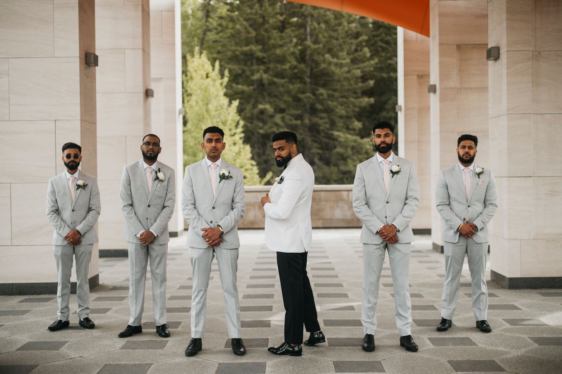 A groom and his groomsmen are posing for a picture in front of a building.