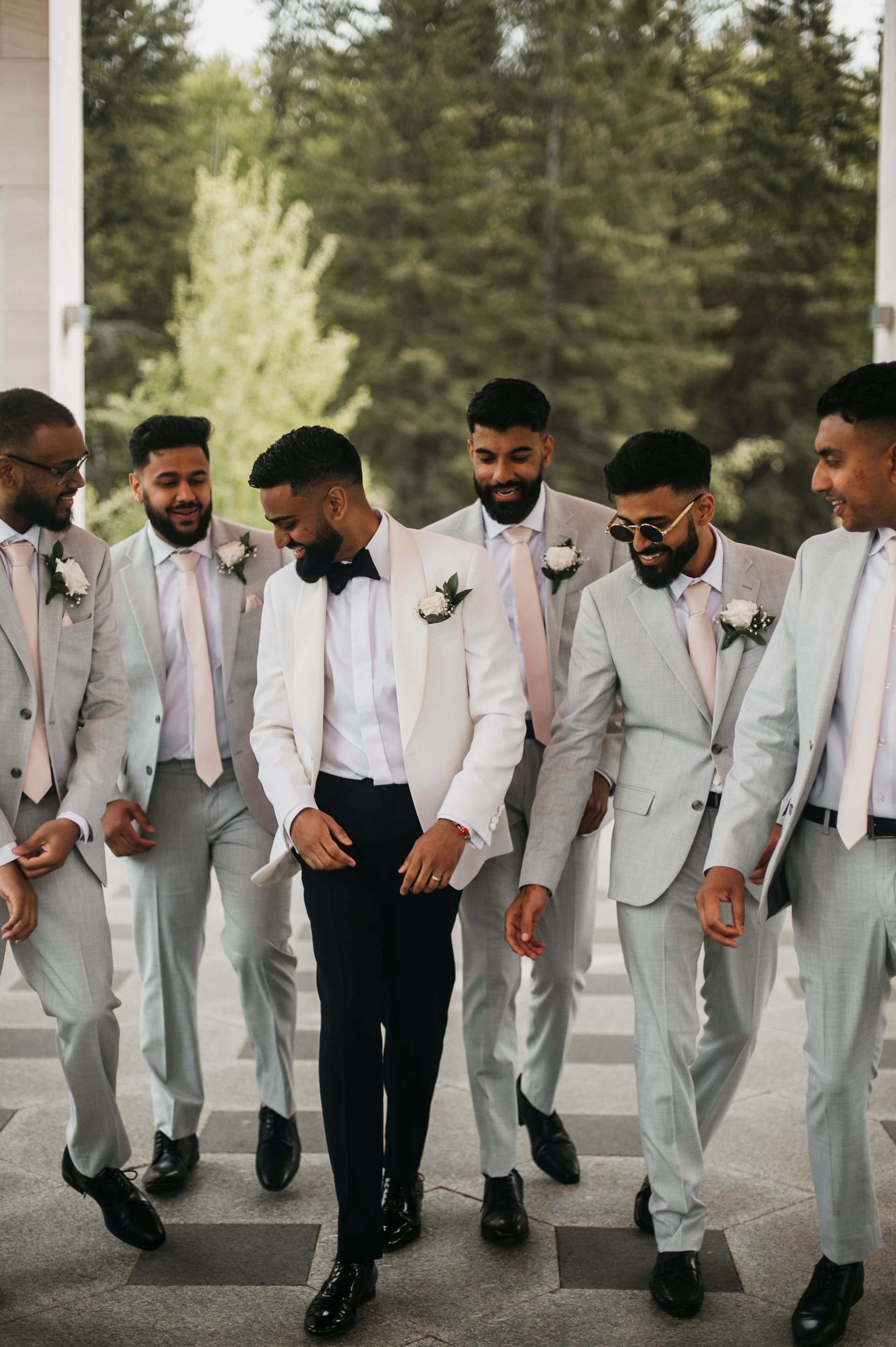 A groom and his groomsmen are walking down a sidewalk.
