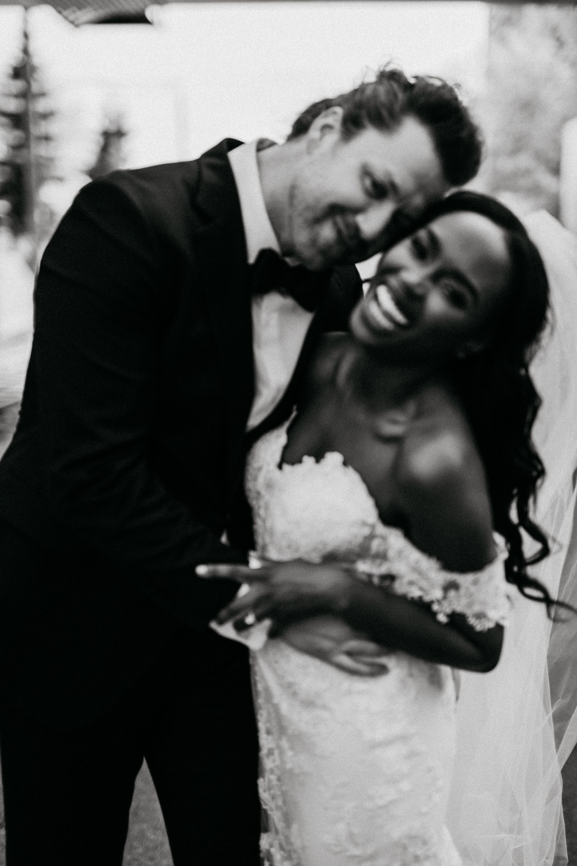 A black and white photo of a bride and groom hugging each other.