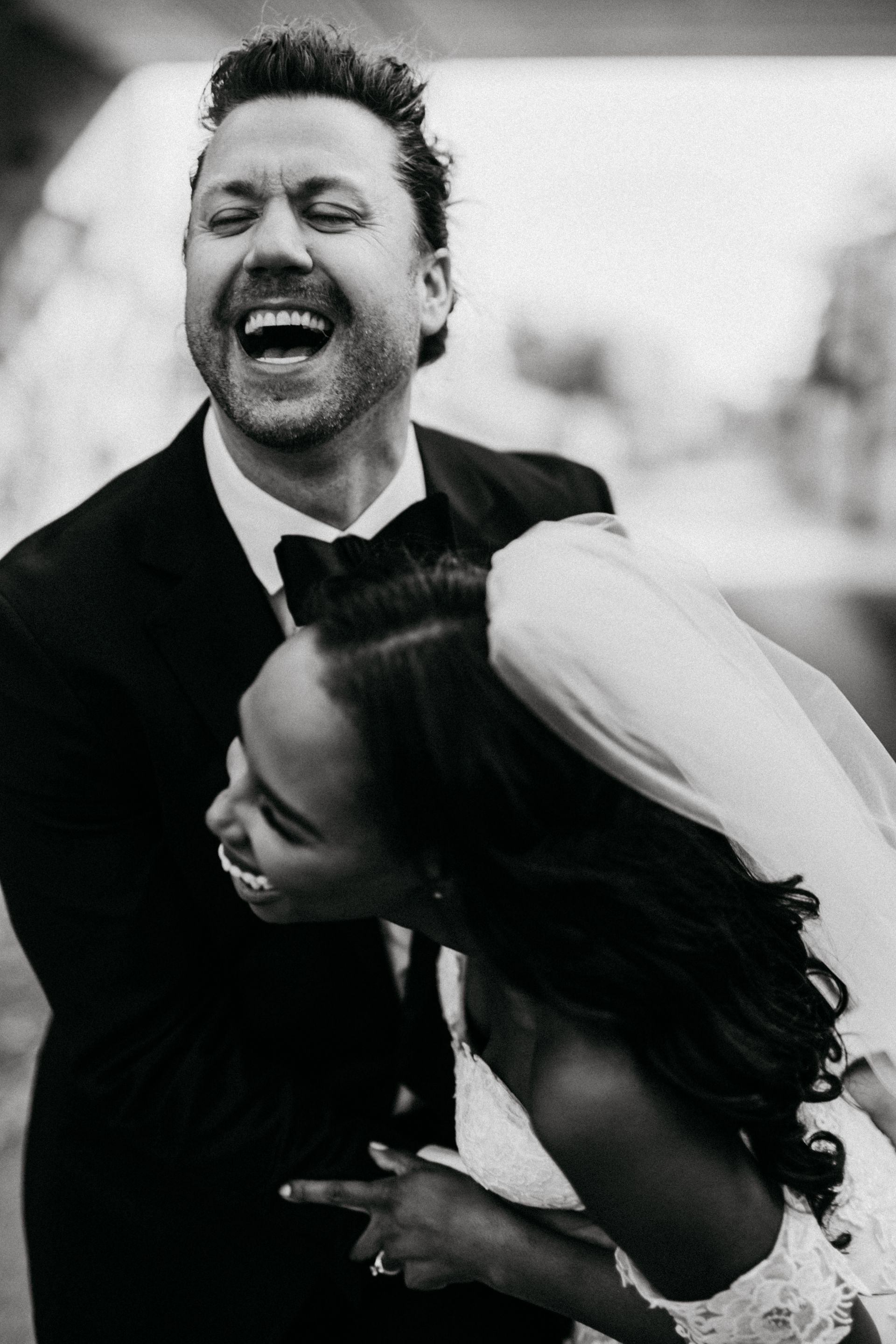 A black and white photo of a bride and groom laughing