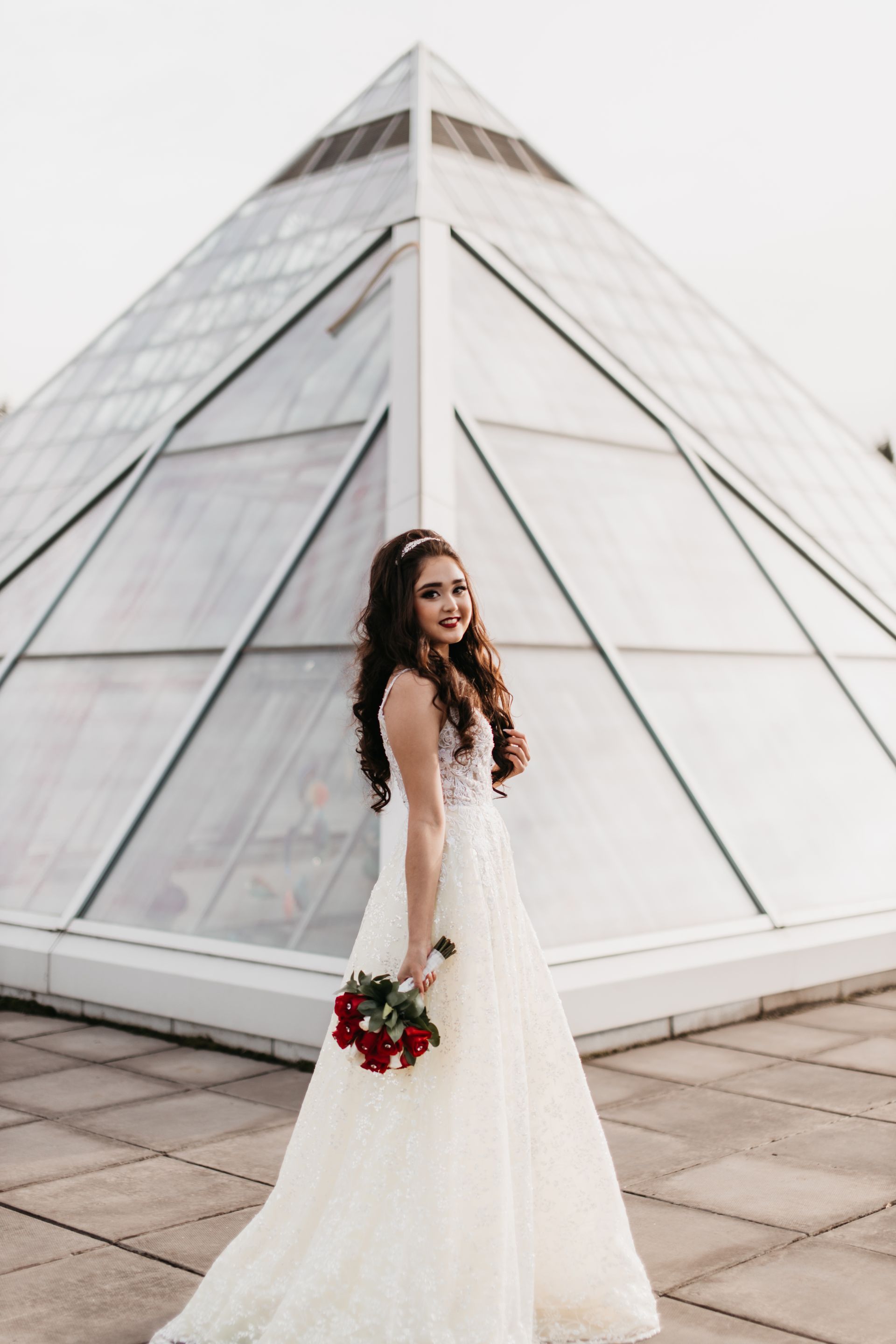 A woman in a wedding dress is standing in front of a pyramid.