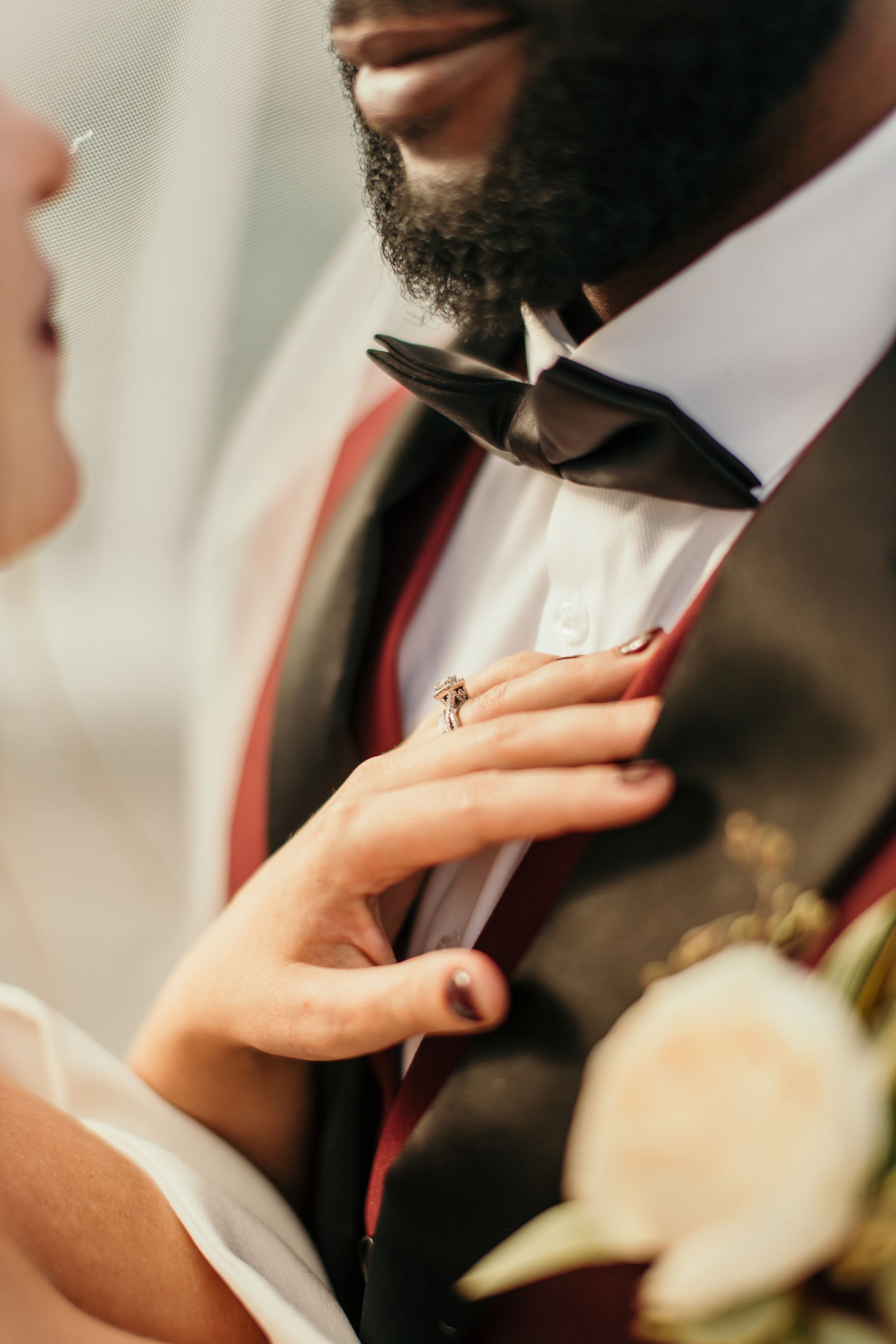 A man in a tuxedo and bow tie has a ring on his finger