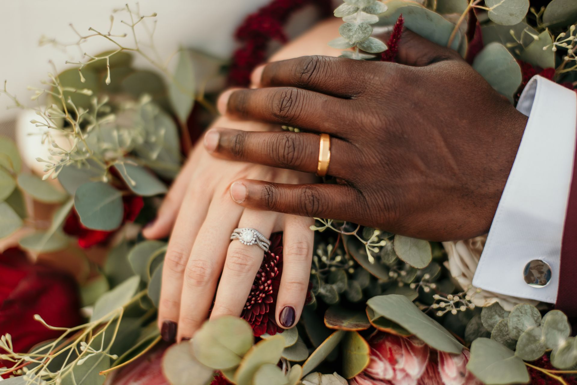 A close up of a bride and groom 's hands with wedding rings.