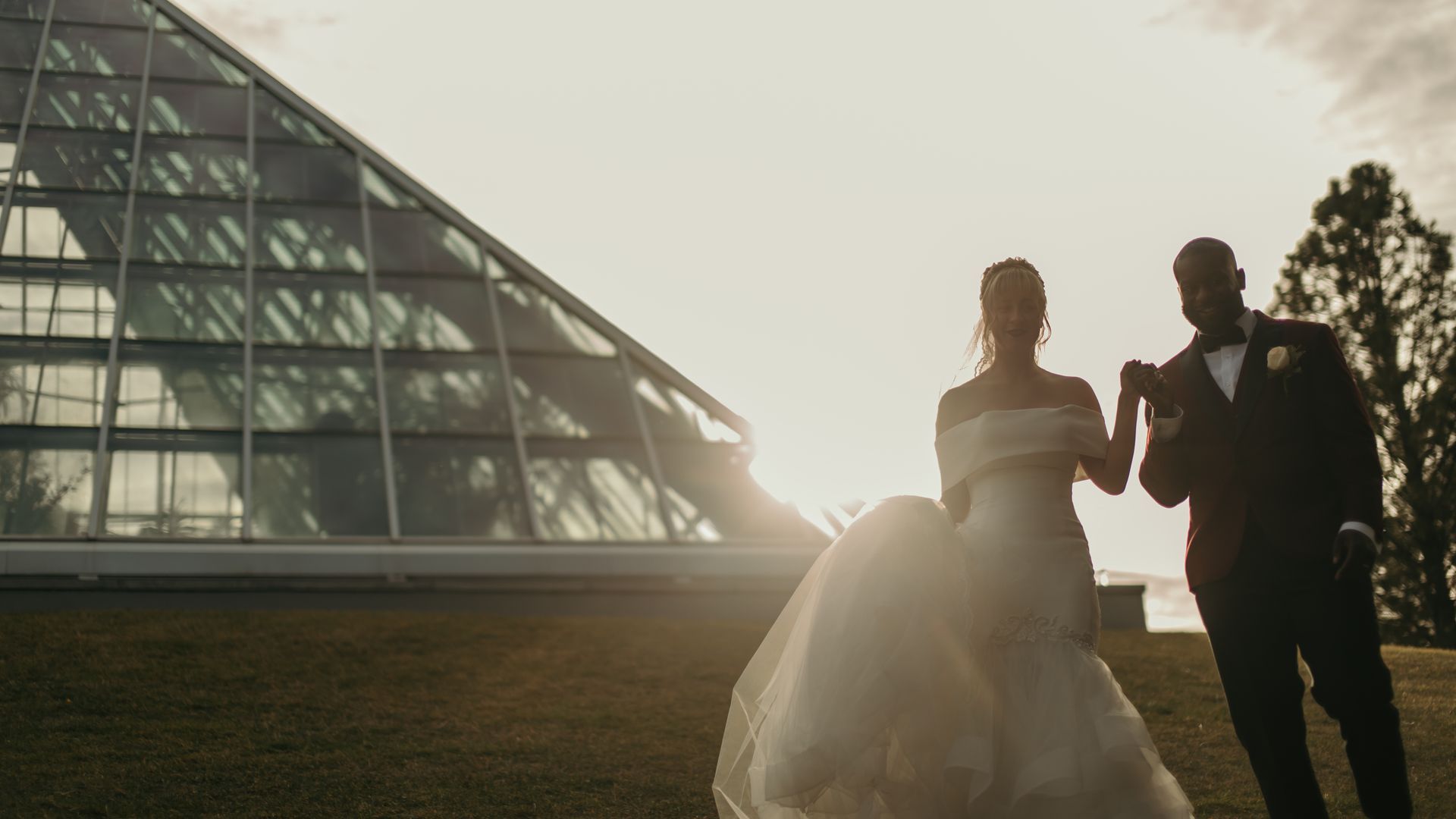 A bride and groom are holding hands in front of a building.