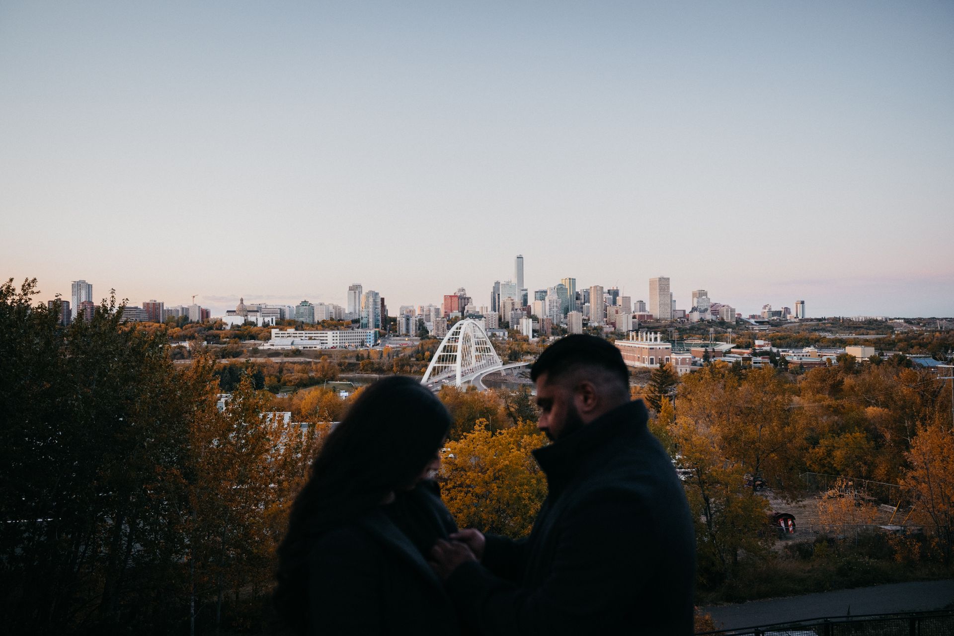 A man and a woman are standing next to each other in front of a city skyline.