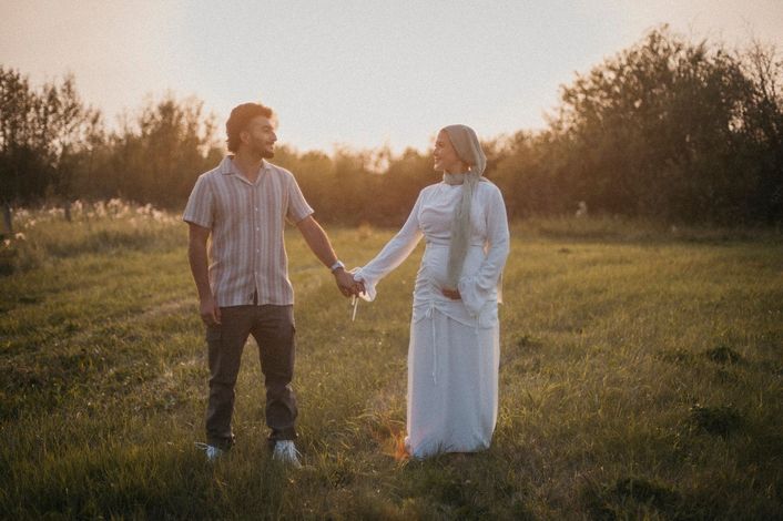 A man and a woman are holding hands in a field.