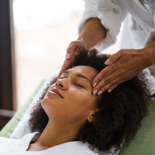 Woman receiving a head massage in a spa. Hands on forehead, eyes closed, relaxed.