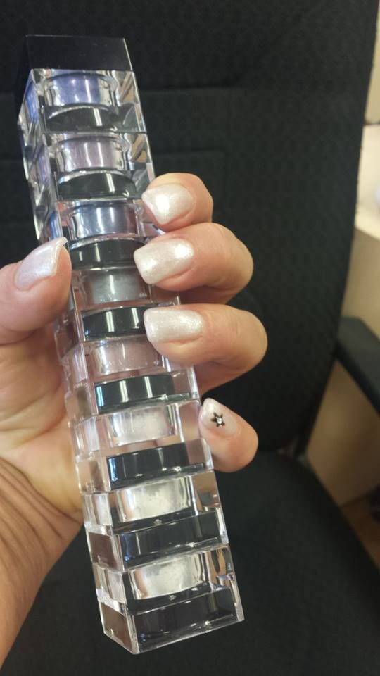Hand holding a clear, layered, rectangular object. Nails have a French manicure and a small jewel.