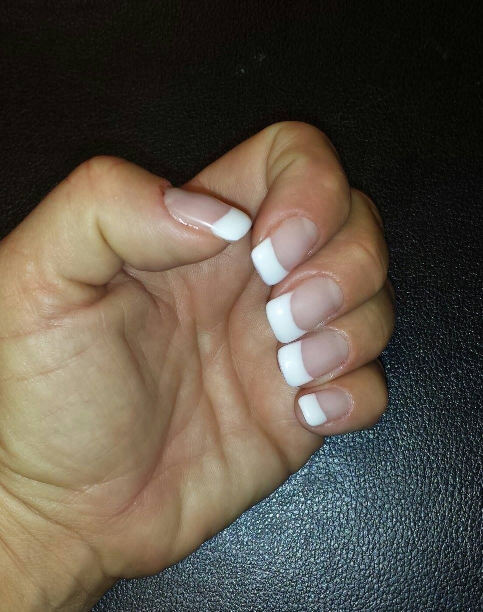 Hand with French manicure nails. White tips on clear nails.