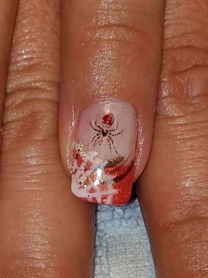 Spider nail art with red, orange, white, and black colors.