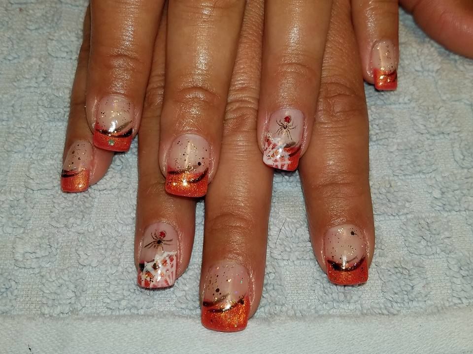 Close-up of hand with orange and white nail art design.