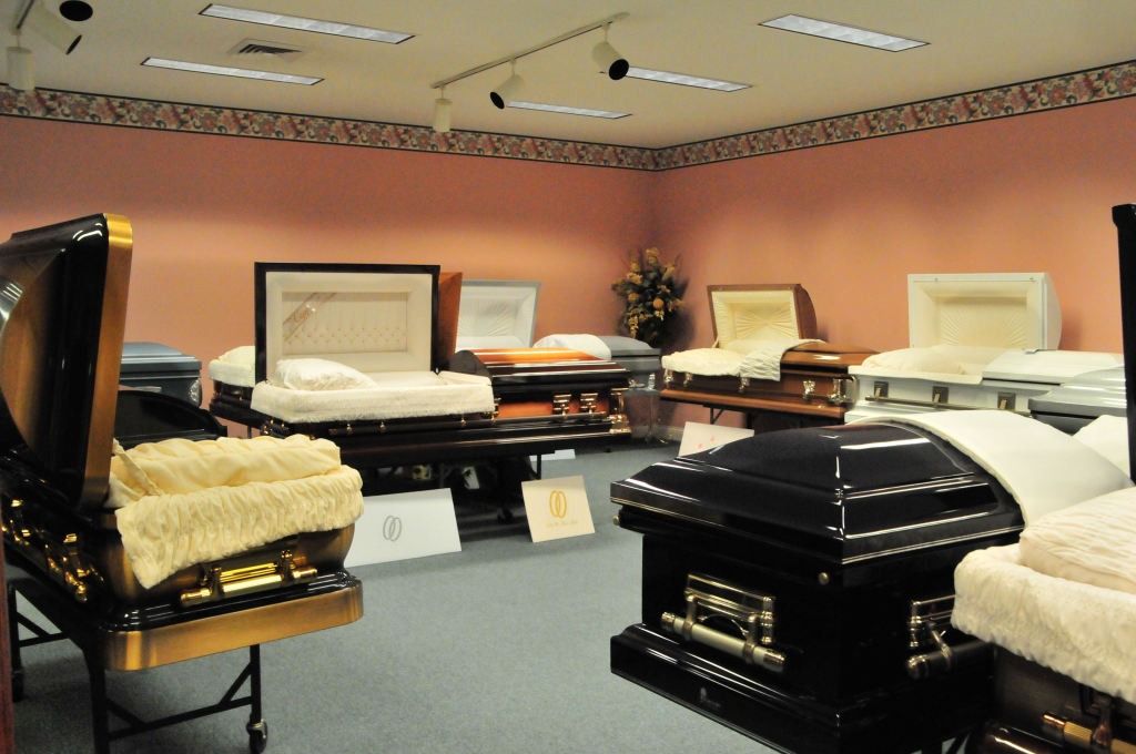 Funeral home showroom with various open caskets.