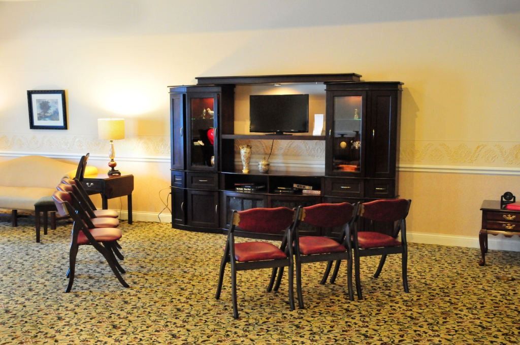 Living room with entertainment center, sofa, chairs, and patterned carpet.