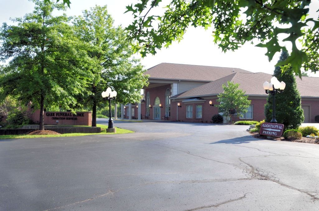 Brick building with columns and trees; entrance to a funeral home.