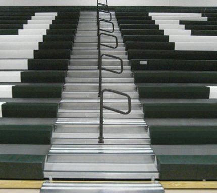 Straight shot of Interkal quarter-turn aisle rails in closed position on an open telescopic bleacher.