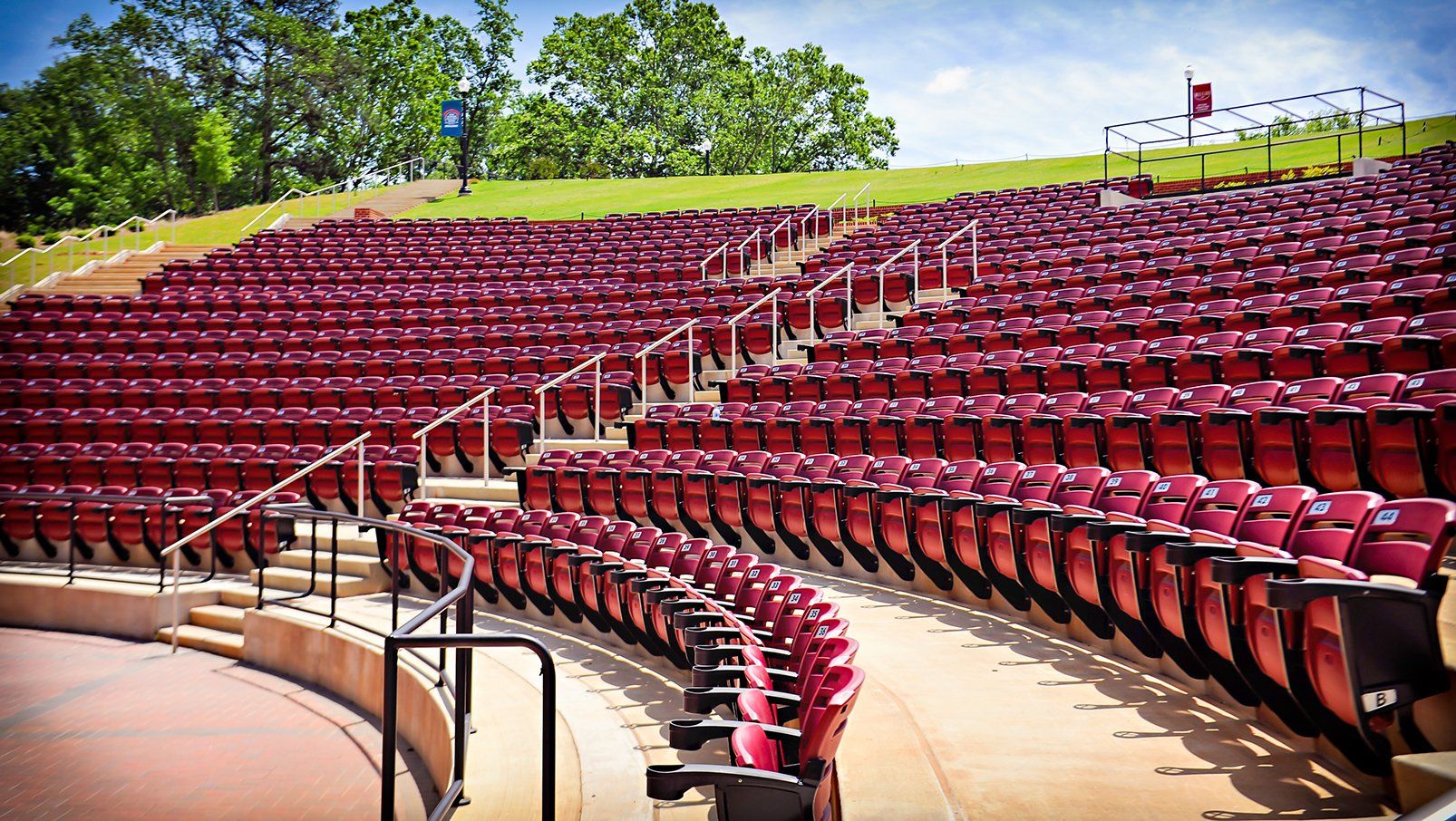 Burgundy Interkal AURA Slat Stadium Chairs with armrests with cupholders in the outdoor amphitheater at Boyd Sweetland.