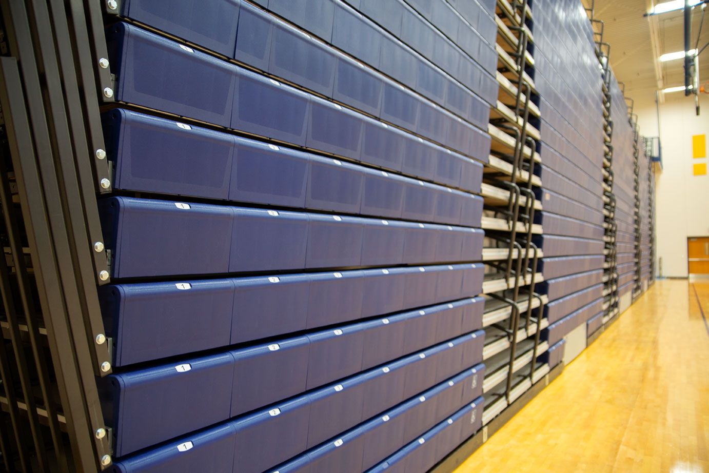 Blue Interkal EXCEL Seat Modules color the massive high-rise telescopic bleacher installation at the Dewitt High School gym.