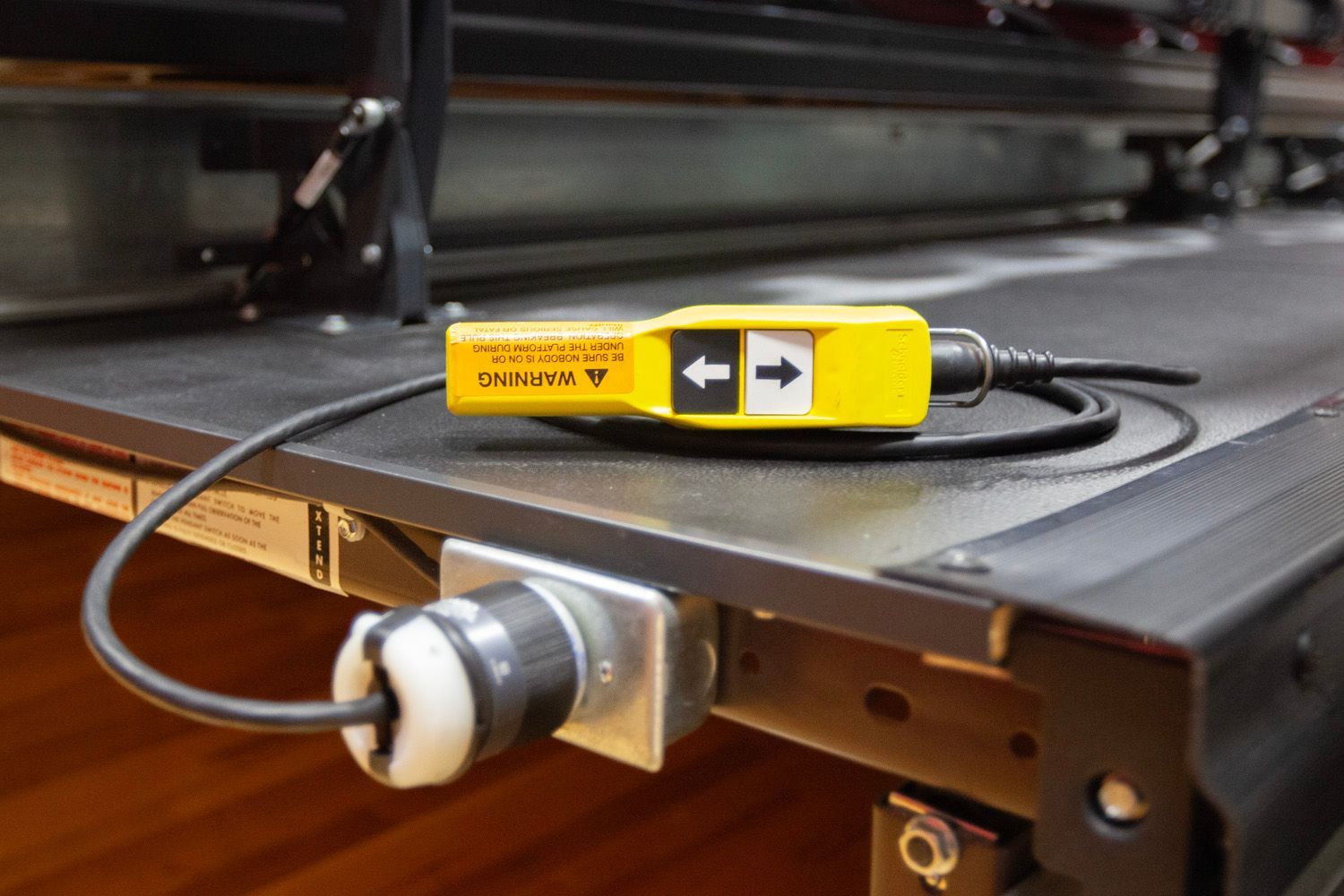 A closeup photo of the telescopic bleacher pendant switch on a platform, plugged into the bleacher and ready for usage.