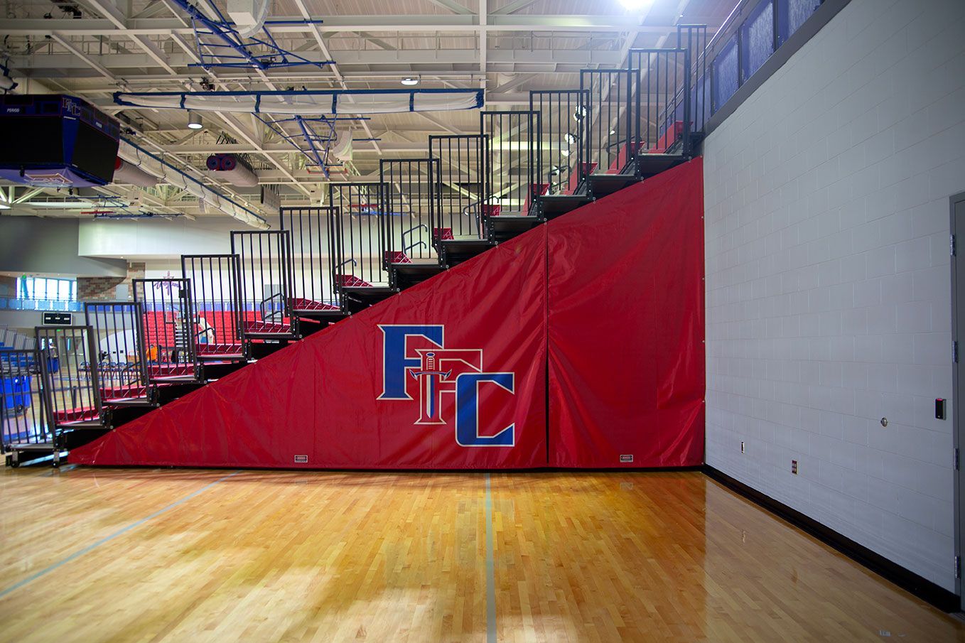 The gymnasium floor at Trojan Arena in CO that features EXCEL Seat Modules in red, white and blue colors for a striking look!