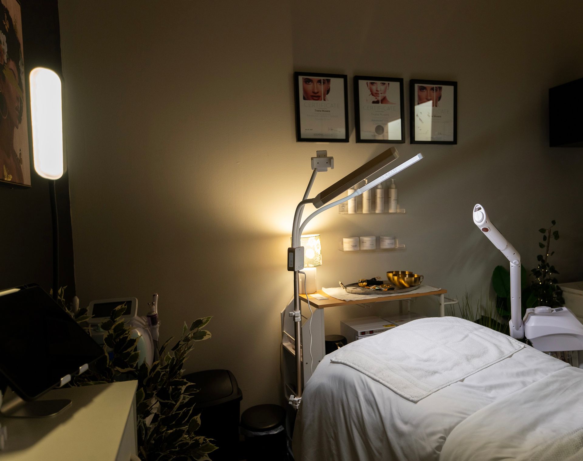 Spa treatment room with a massage bed, lamps, and a small table with supplies.