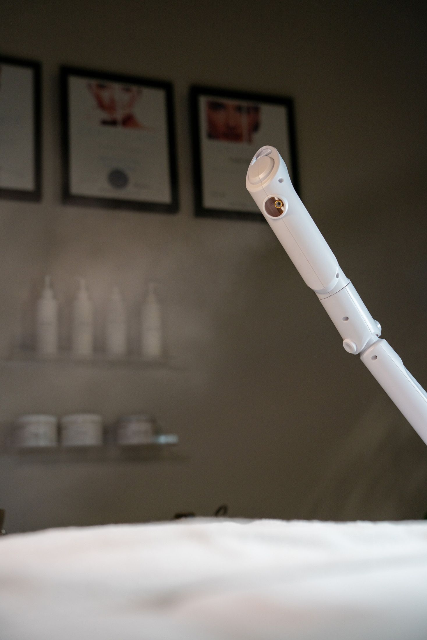 Steam wand with mist, in a spa-like setting. Certificates and bottles on a shelf in the background.