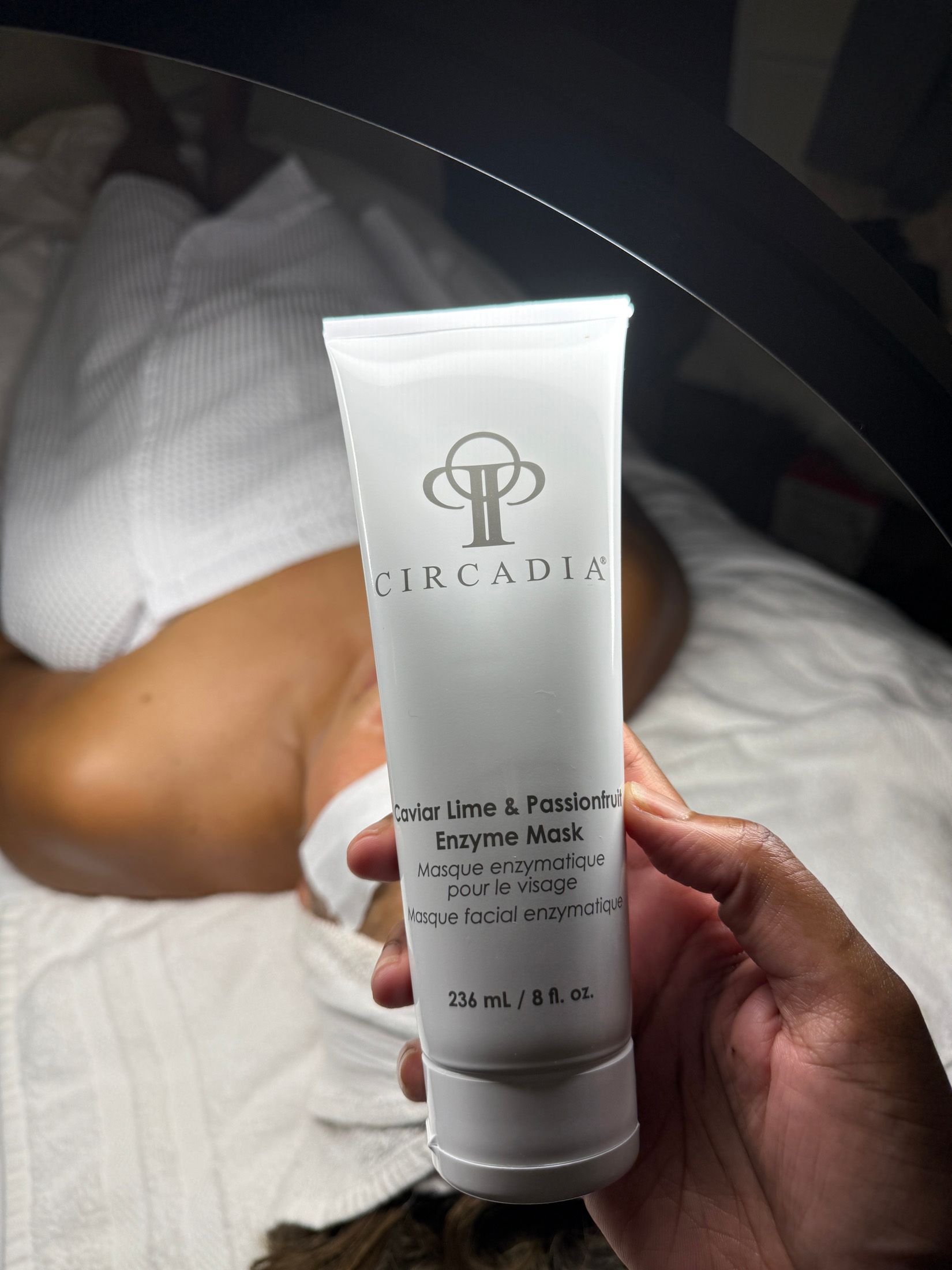 Person holding a white tube of skincare product labeled 