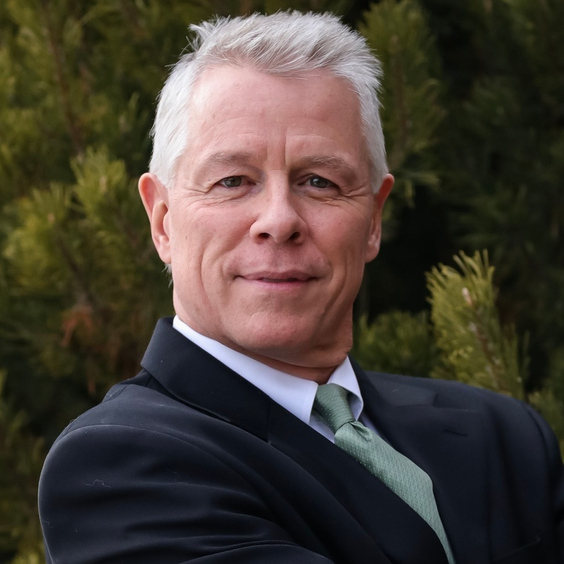 A man in a suit and tie stands with his arms crossed