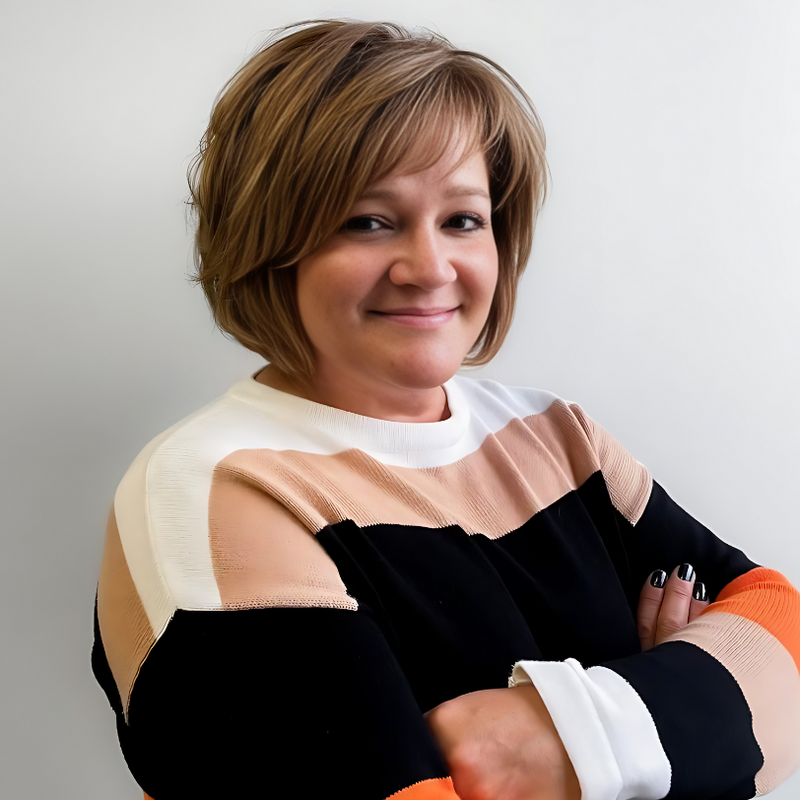 A woman with her arms crossed is smiling for the camera
