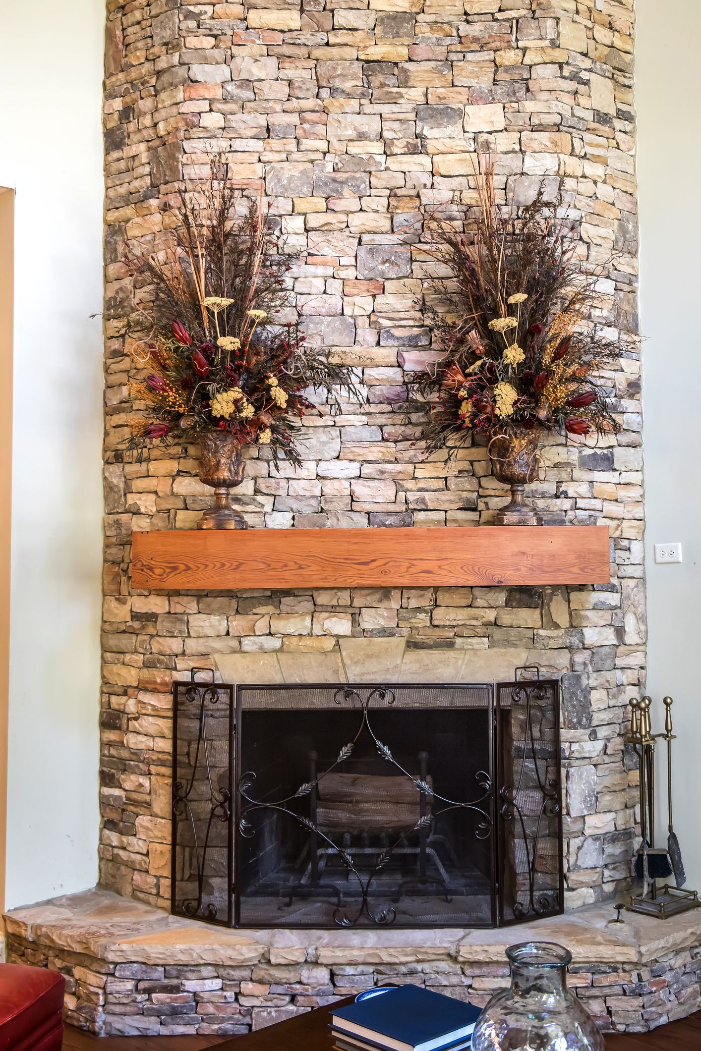 cedar mantle on grey stone fireplace with floral decorations