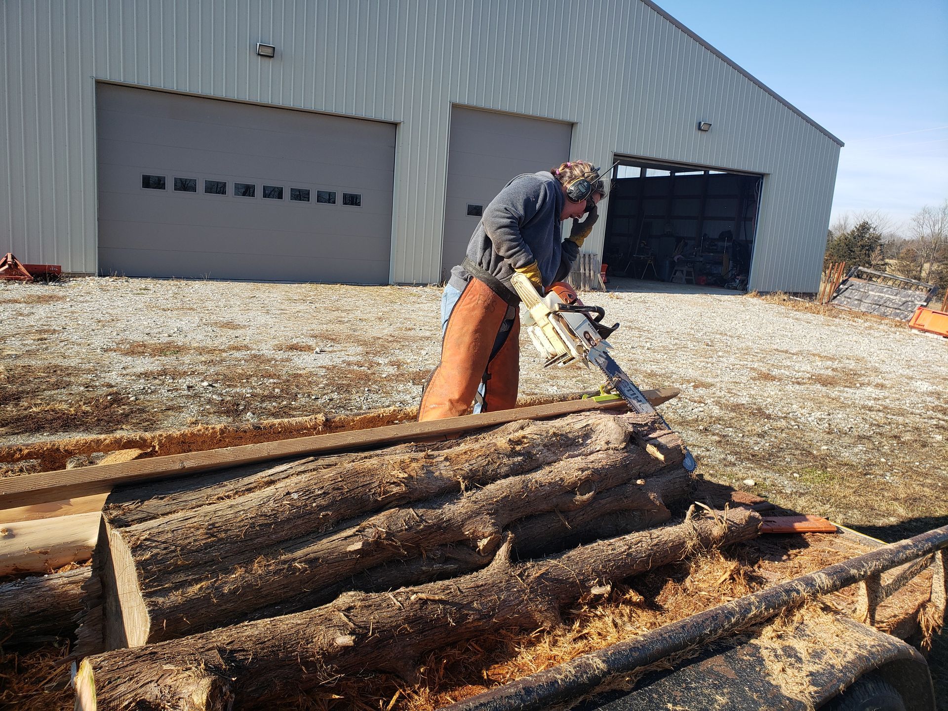 Snellen Wood Products employee using a chainsaw on cedar logs