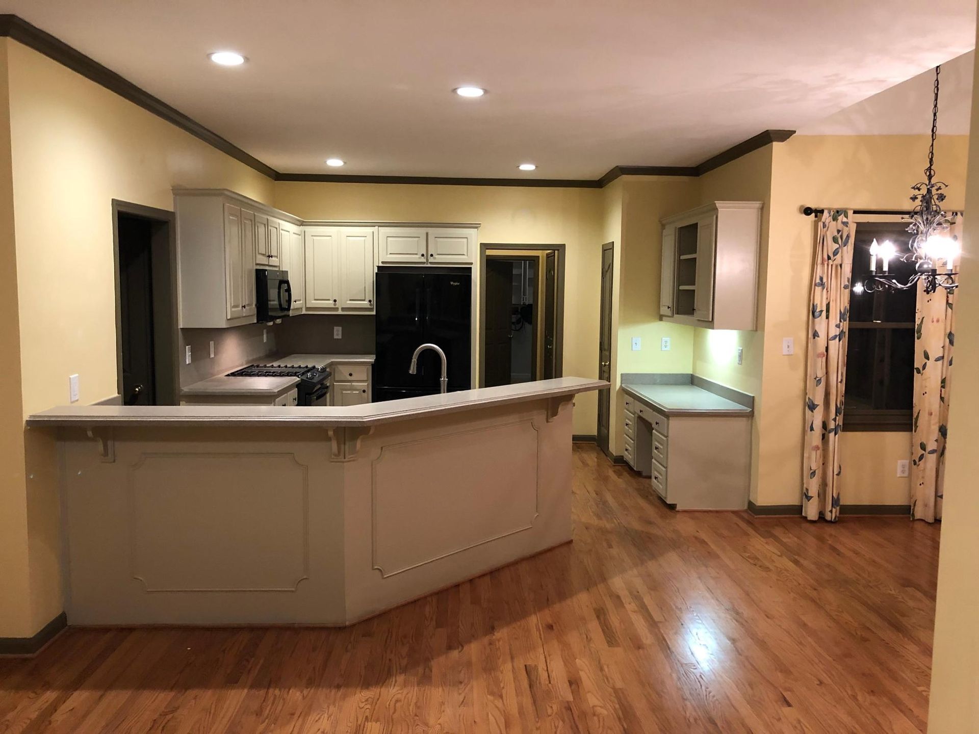An empty kitchen with hardwood floors and yellow walls
