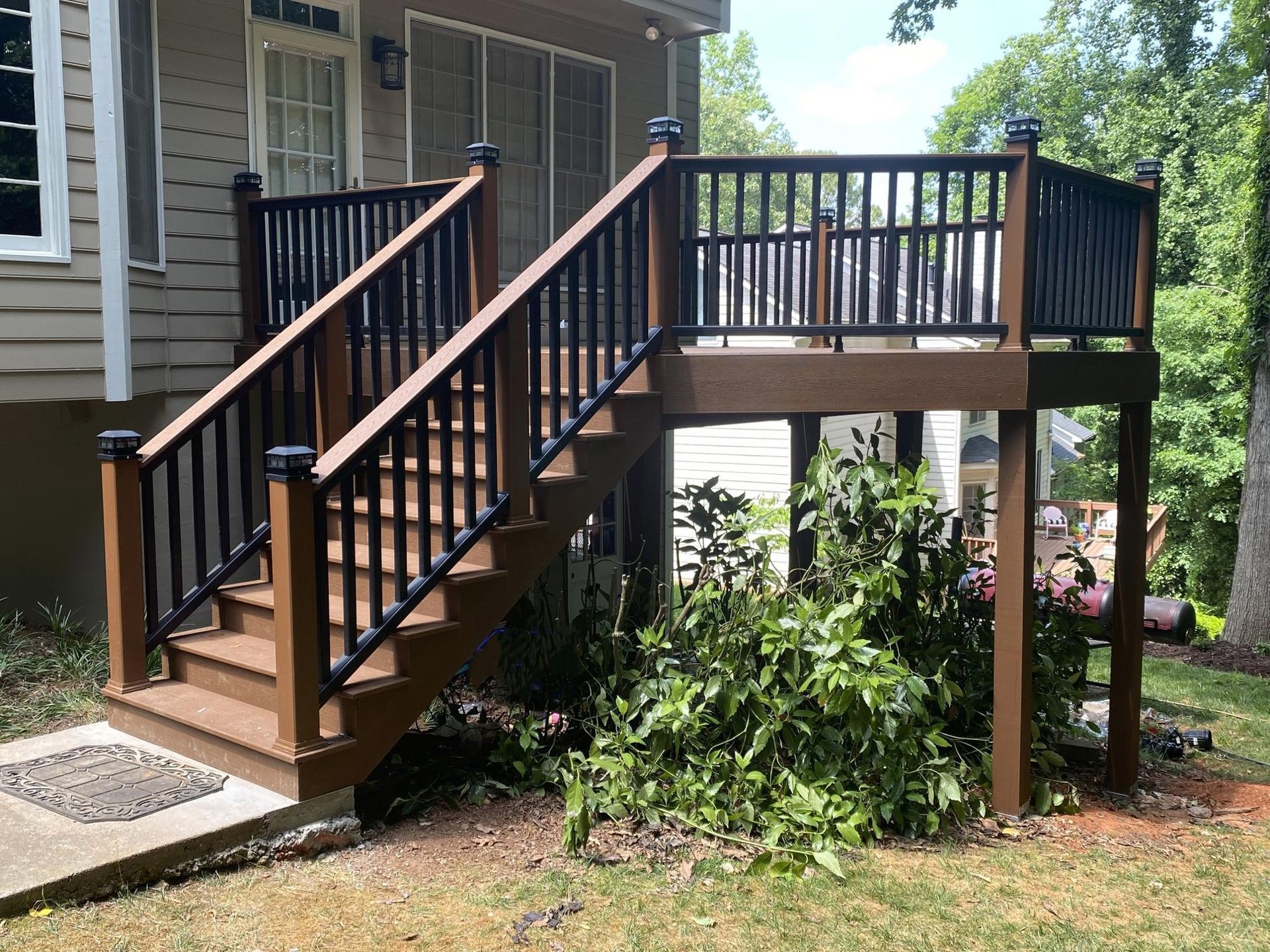 A wooden deck with a black railing and trees in the background.