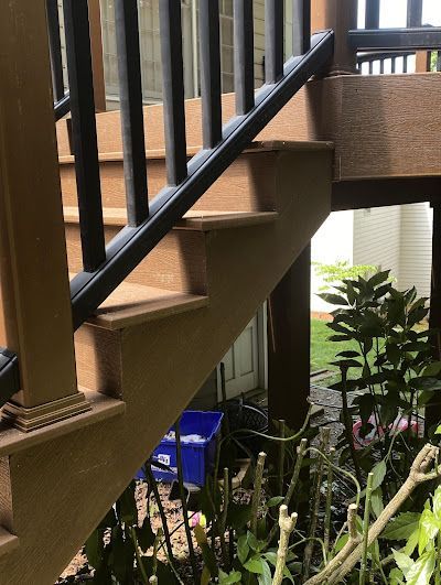 A close up of a wooden staircase with a black railing