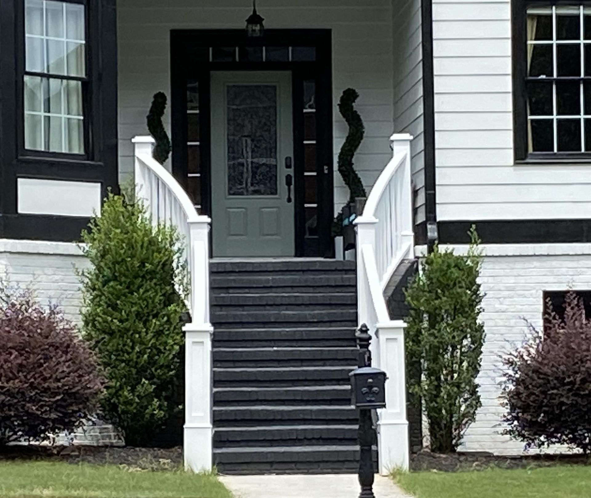 A black and white house with stairs leading up to the front door