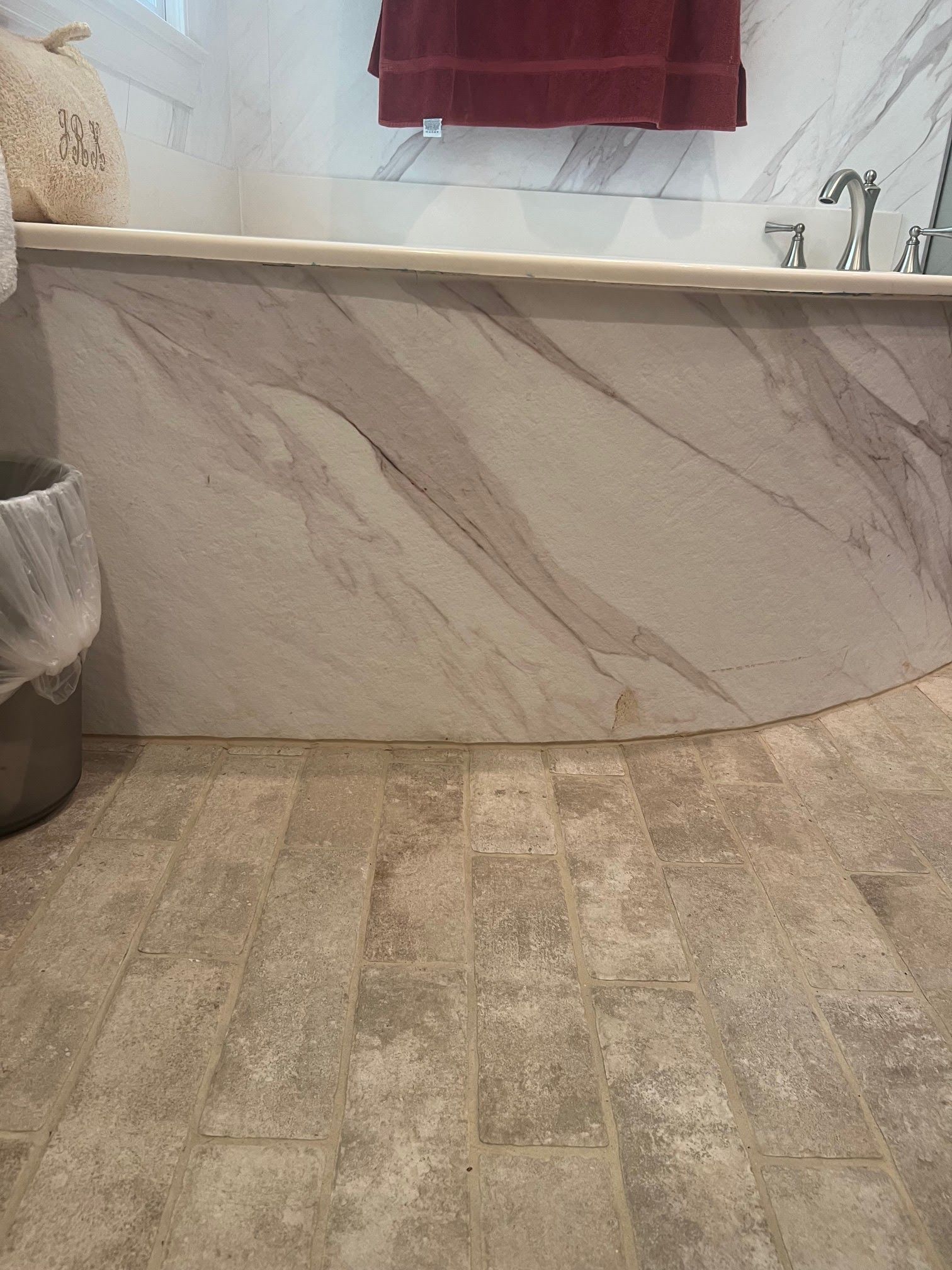 A bathroom with a bathtub and a trash can.