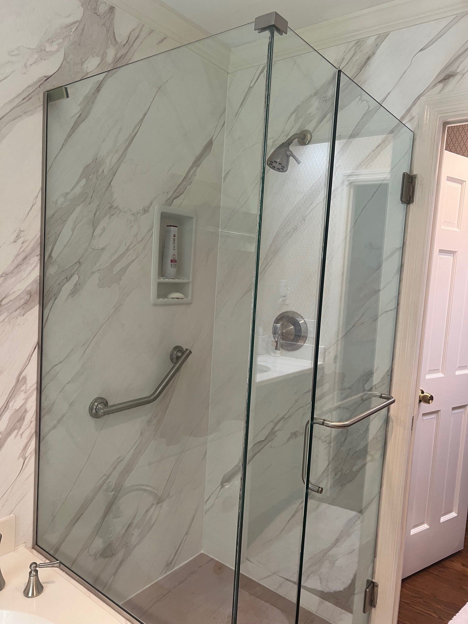 A bathroom with a glass shower door and marble walls.