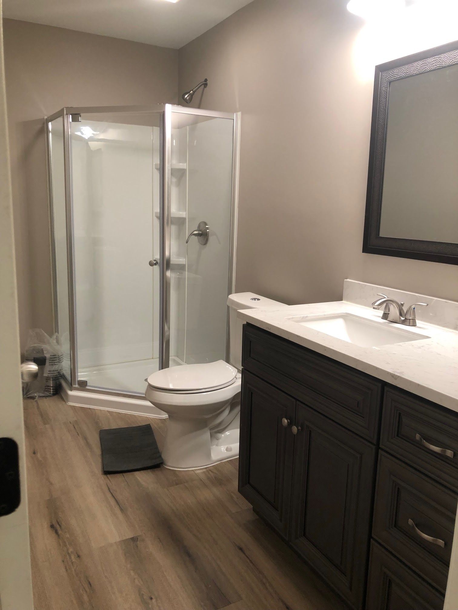 A bathroom with a toilet , sink , shower and mirror.