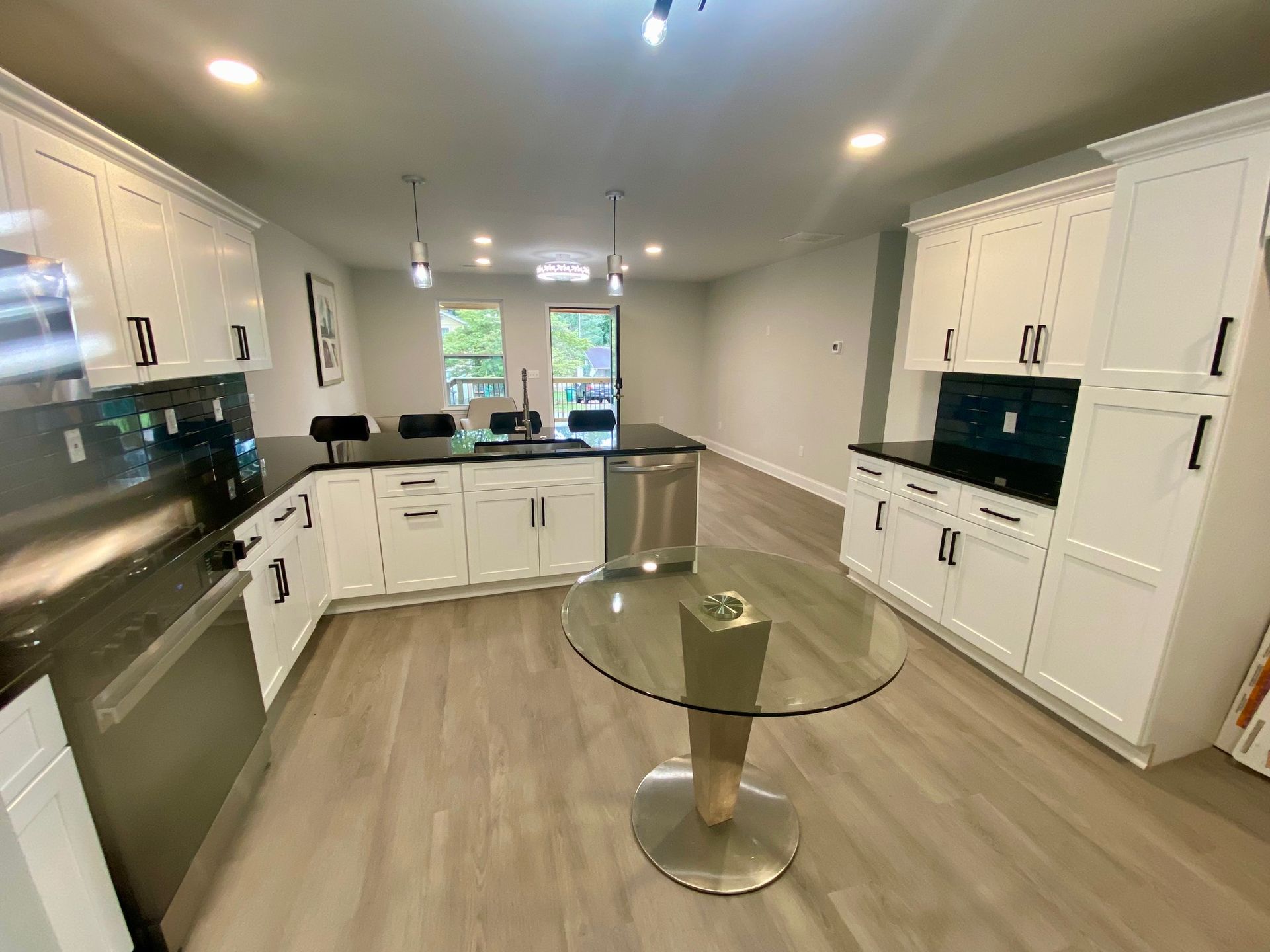 A kitchen with white cabinets and stainless steel appliances and a round glass table.