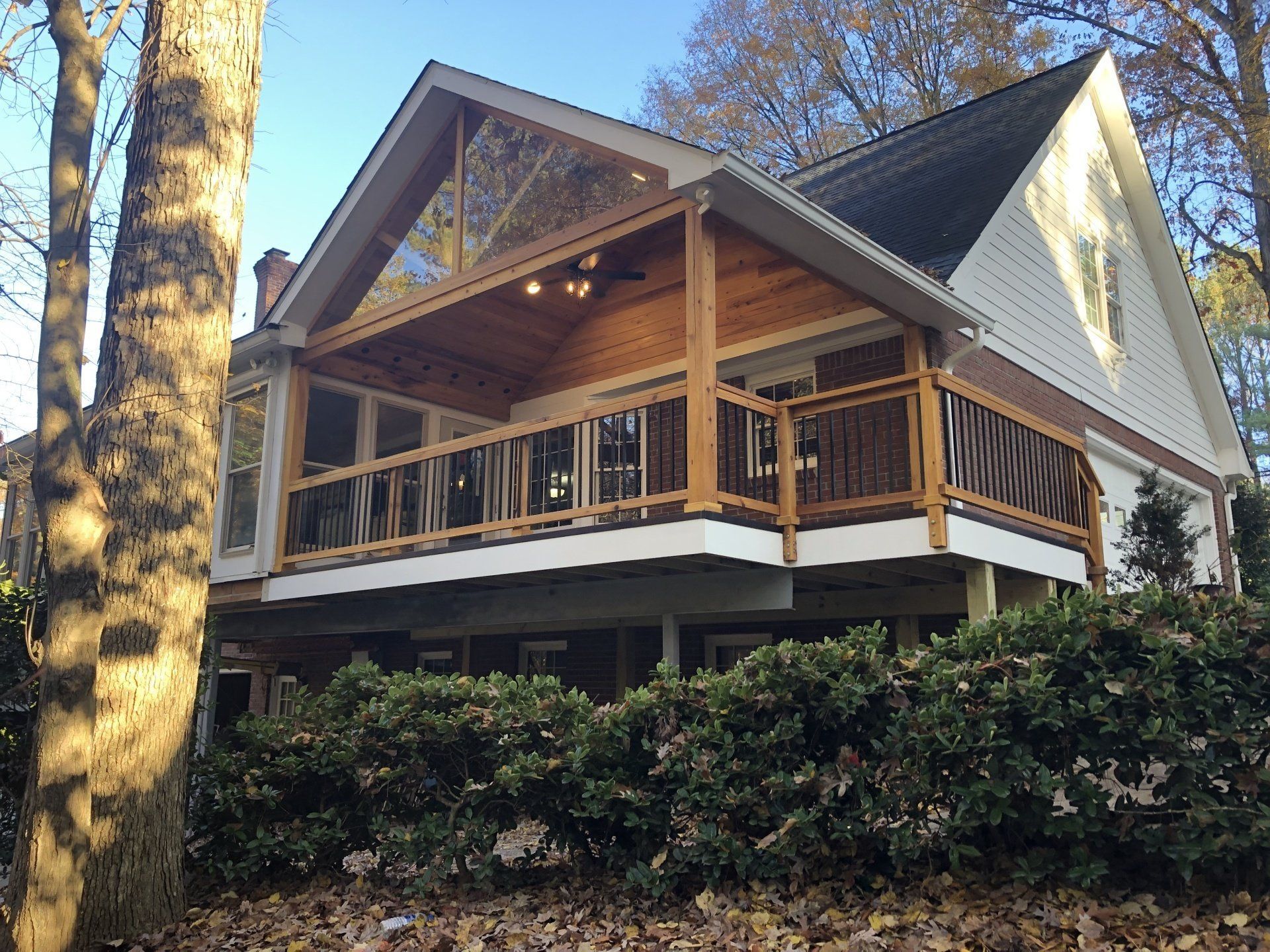 A white house with a large wooden deck surrounded by trees.