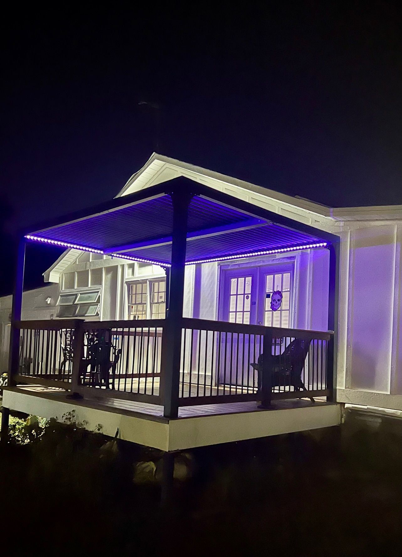 A house with a porch and purple lights on it at night.