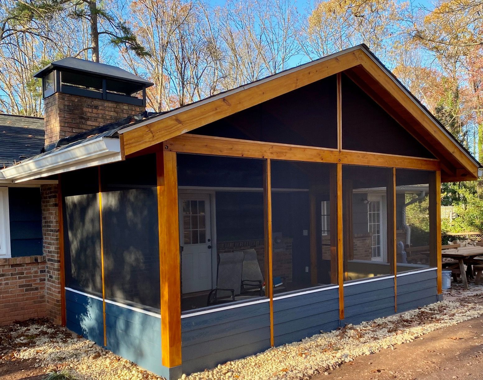 A screened in porch on the side of a house.