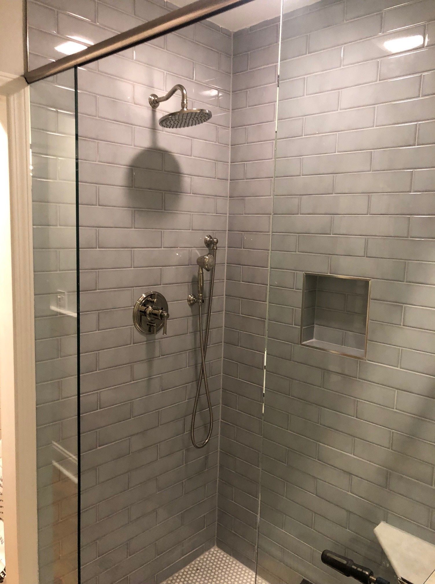 A walk in shower with a glass door and a shower head.
