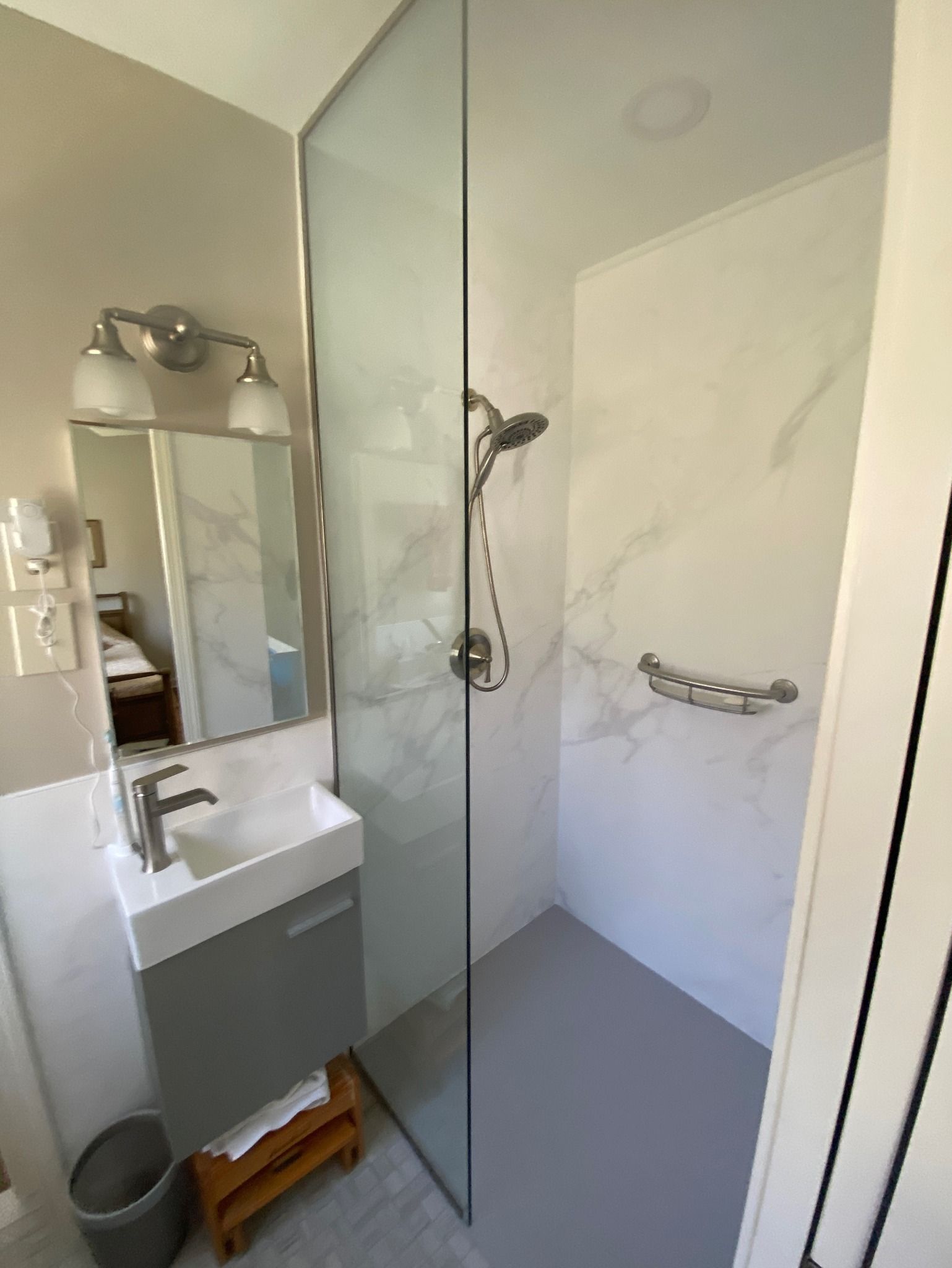 A bathroom with a walk in shower , sink and mirror.