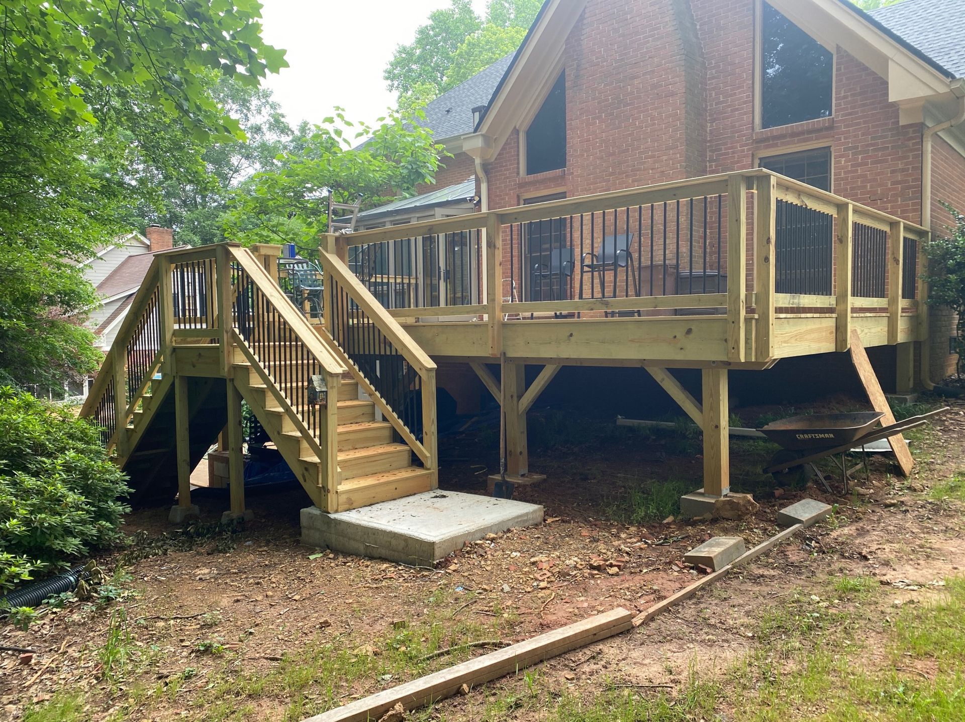 A wooden deck with stairs is in front of a brick house.