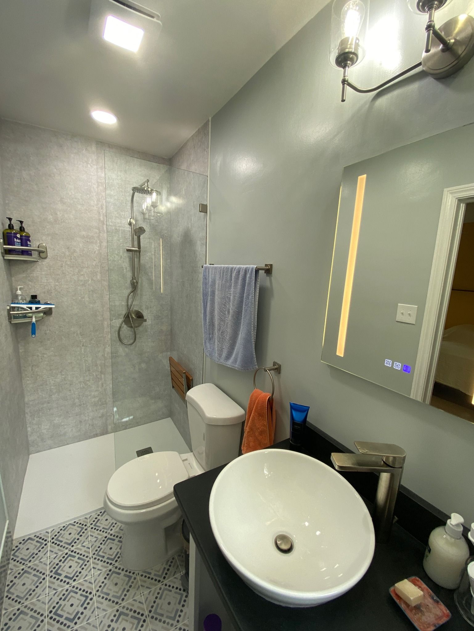 A bathroom with a toilet , sink , mirror and shower.
